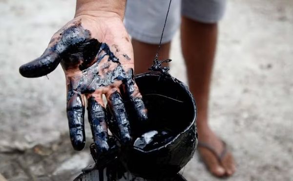 Agricultor Sidrônio Moreira segura recipiente com petróleo cru encontrado após perfuração de poço em propriedade rural de Tabule