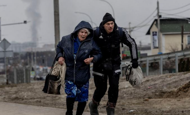 Un hombre ayuda a una anciana a escapar de un fuerte bombardeo en Irpin, cerca de Kiev, Ucrania, el 6 de marzo de 2022. Foto: REUTERS/Carlos Barria