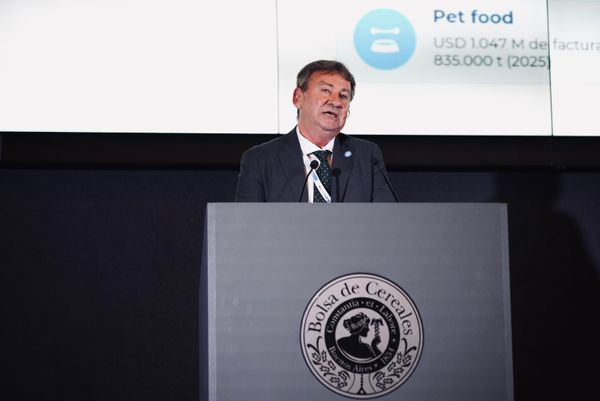 Hombre de traje hablando en un atril con el logo de la Bolsa de Cereales; detrás, pantalla con datos de pet food