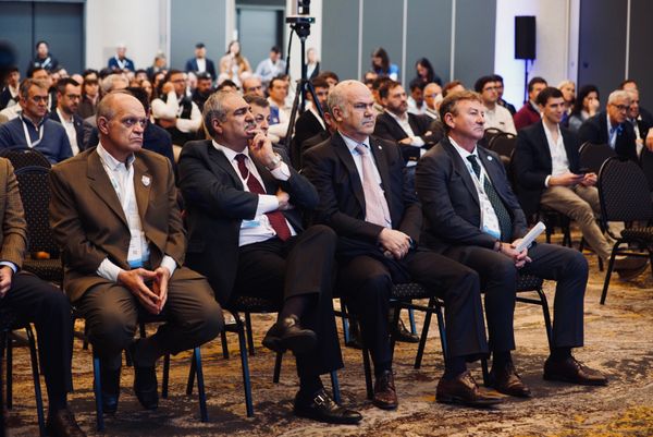 Funcionarios y productores sentados en primera fila durante un evento del sector agropecuario, con público de fondo