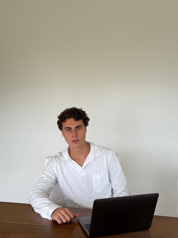 Santino Calcaterra sentado frente a una laptop en un escritorio de madera