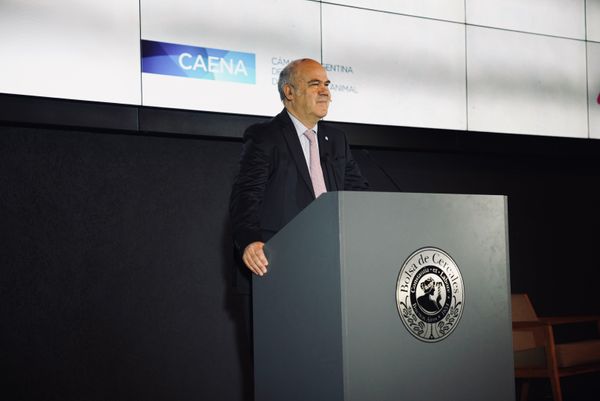 Hombre habla en un atril de la Bolsa de Cereales junto al logo de CAENA