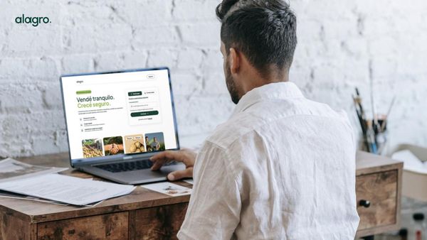 Hombre de espaldas usa una notebook con la plataforma Alagro, que muestra productos agropecuarios y el mensaje "Vendé tranquilo. Creció seguro.