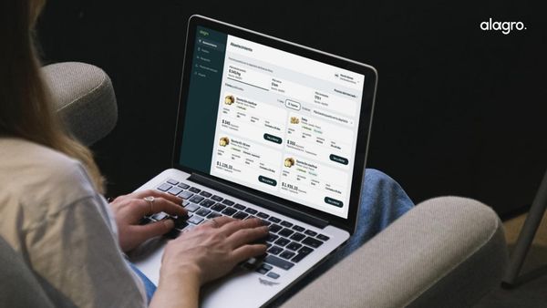 Persona usando una notebook con una plataforma de comercialización agropecuaria en pantalla, con listados de productos y precios; logo de Alagro.