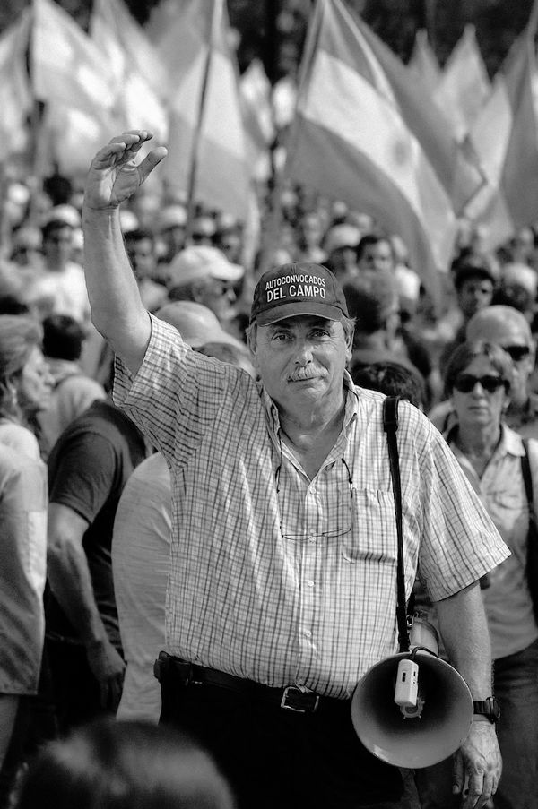 Hombre con gorra de Autoconvocados del Campo, megáfono en mano, frente a una multitud con banderas