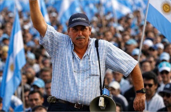 Hombre con gorra de Autoconvocados y megáfono en una protesta rodeado de banderas argentinas