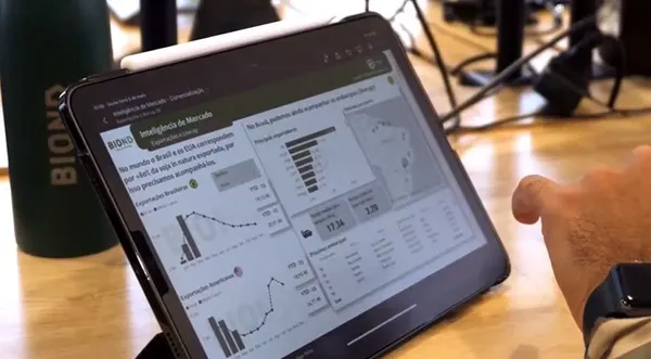 Tablet con panel de inteligencia de mercado con gráficos de exportaciones de soja de Brasil y precios, sobre una mesa de madera