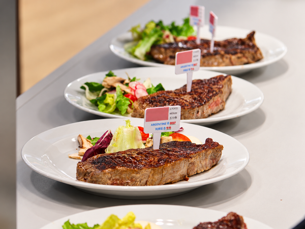 Tres platos con cortes de carne vacuna argentina y ensalada, con carteles "Argentine Beef