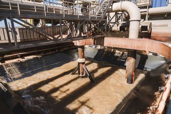 Tanque industrial con agua turbia marrón, caños metálicos y pasarelas de hierro