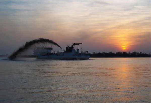 Draga de succión expulsando sedimento en el río Paraná al atardecer, en la hidrovía